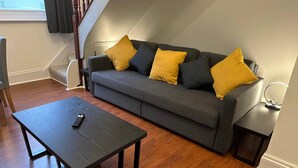 A modern living room with a grey sofa, yellow cushions, a wooden coffee table, and a small side table with a lamp. - 2 Bedroom House in Central Winchester (Winchester)