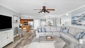 A spacious living room with a large sectional sofa, a flat-screen TV, and a ceiling fan.