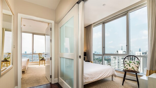 A bedroom with a large window, a bed, a chair, and a view of the cityscape. - Serviced 2 Bed Scenic Sky Villas - Check in From 15h to 22h Only (Bangkok)