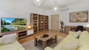 Ein Wohnzimmer mit Fernseher, Holzregal, Sofa, Couchtisch und Dekorationselementen.