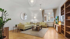Ein Wohnzimmer mit zwei Sofas, einem Couchtisch, einem runden Spiegel, einer Zimmerpflanze und einem Bücherregal.