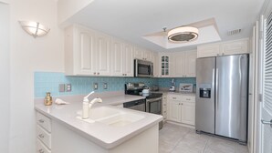 A modern kitchen with white cabinets, a stainless steel refrigerator, a microwave, and a dishwasher. - A view of Gulf of Mexico, plus access to all the resort amenities! A3214C (Placida)