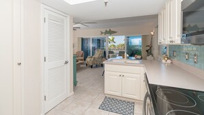 A kitchen with a large island, white cabinetry, and a view to the outside. - A view of Gulf of Mexico, plus access to all the resort amenities! A3214C (Placida)