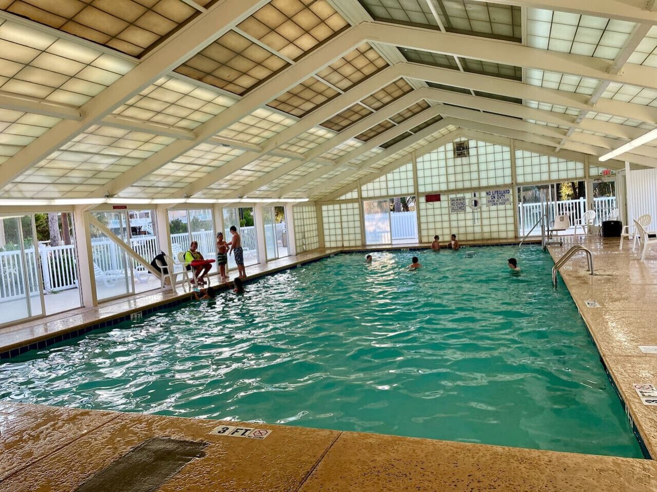 An indoor swimming pool with a covered roof and glass walls.