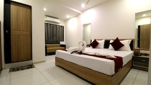 A hotel room with a large bed, a wooden floor, a mirror, a wardrobe, and a bathroom. - Hotel Near Me (Rajkot)