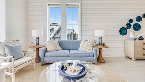 A living room with a blue sofa, white walls, and a large window.
