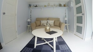 A room with a round white table, beige sofa, and two side tables with lamps.