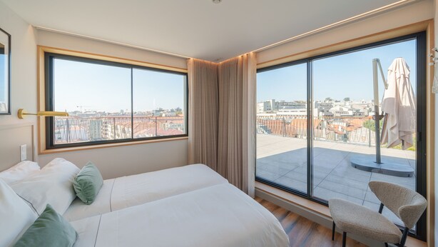A hotel room with two beds, large windows, and a view of the city.