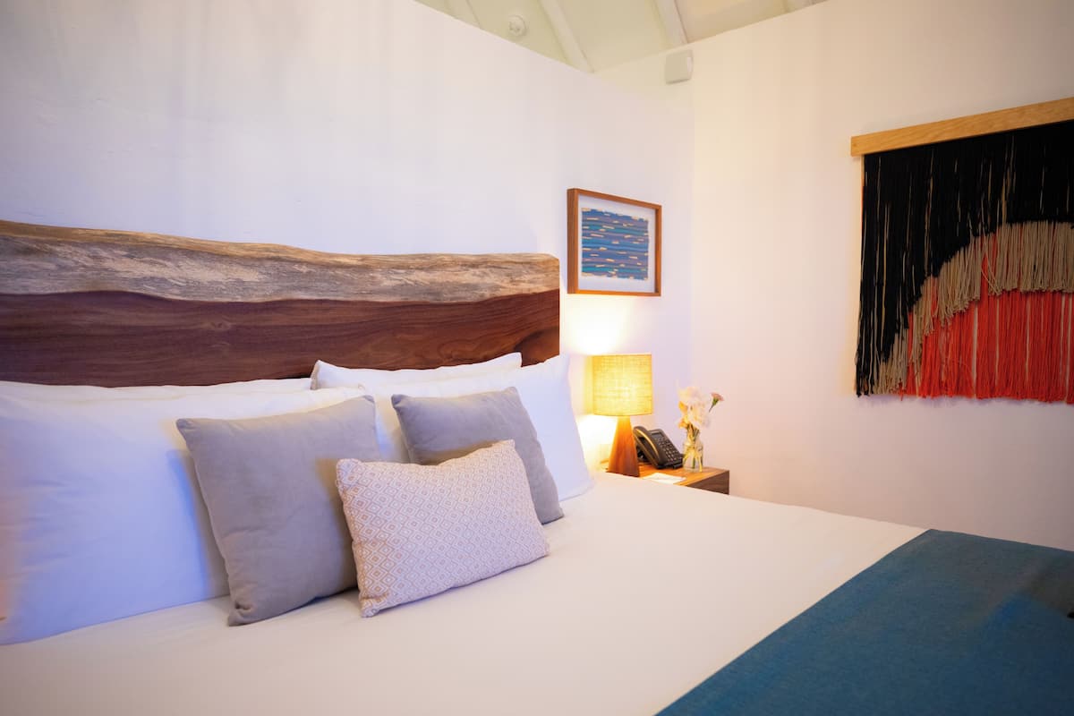 A neatly made bed with a wooden headboard, a bedside lamp, and a framed picture on the wall.