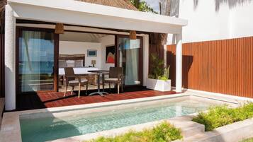 A modern villa with a pool, a dining area, and a bedroom with a large window overlooking the sea.
