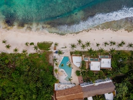 Oversigtsbillede af et resort med swimmingpool, strand og palmer.