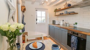 A modern kitchen with grey cabinets, a wooden countertop, and a built-in oven. There is a white door leading to another room, and a star decoration on the wall.