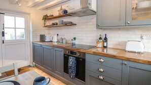 A modern kitchen with grey cabinets, a wooden countertop, a built-in oven, and a window with a view.