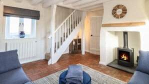 A cozy living room with a fireplace, a staircase, and a view of the outside.