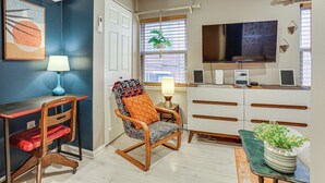 A modern living room with a desk, chair, TV, and a potted plant. - Centrally Located Philadelphia Townhome w/ Patio! (Philadelphia)
