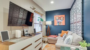 A modern living room with a flat-screen TV, a desk with a computer, a sofa, and decorative pillows. - Centrally Located Philadelphia Townhome w/ Patio! (Philadelphia)