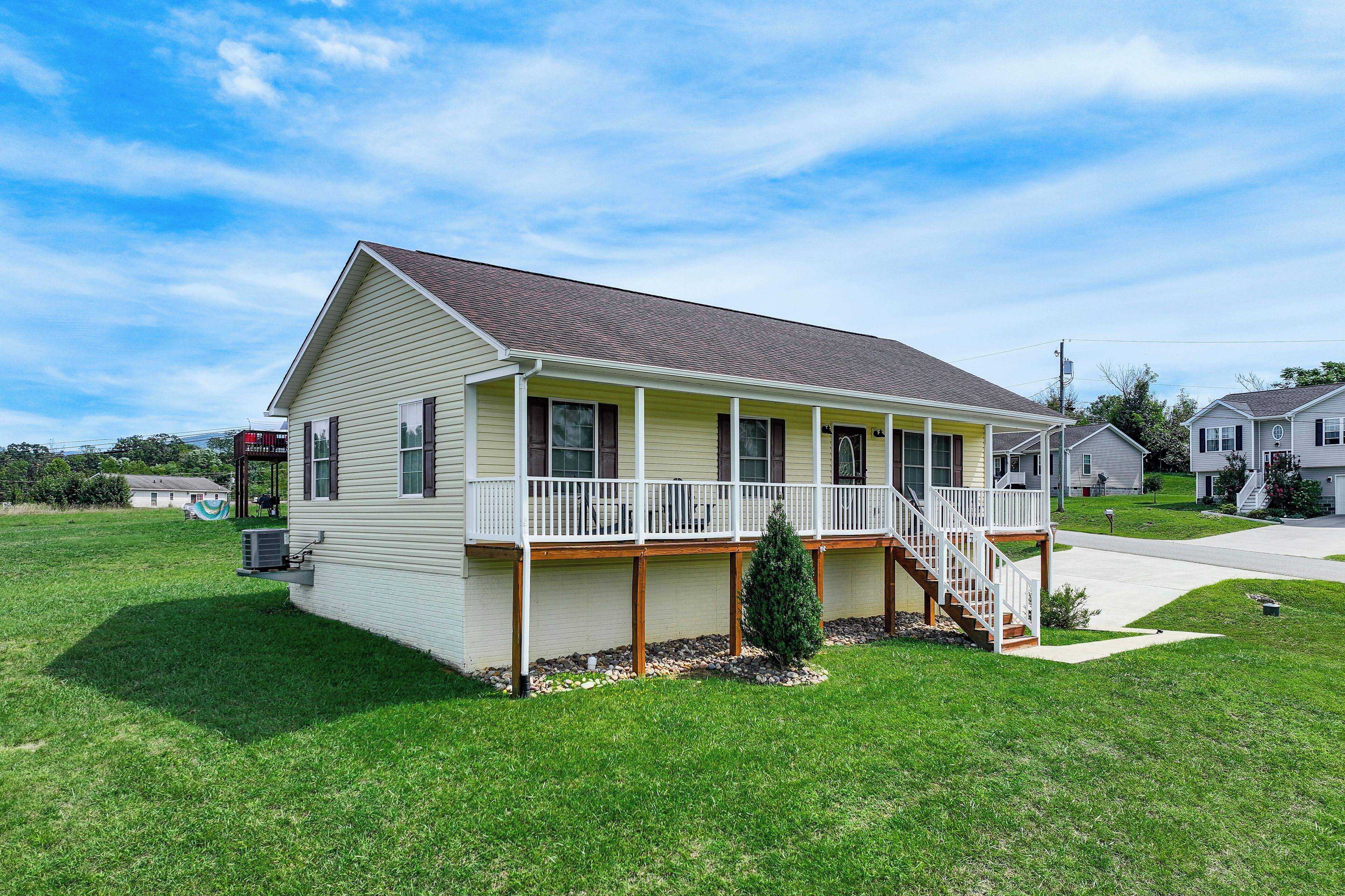 A single-story house with a front porch, a small front yard, and a clear sky.
