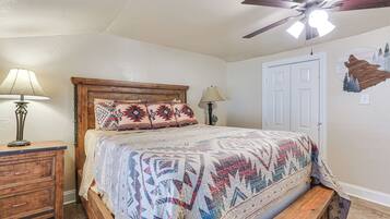 A bedroom with a wooden bed, two bedside lamps, a ceiling fan, and a door.