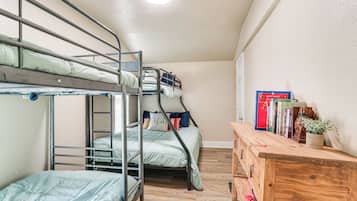Een slaapkamer met een stapelbed, een houten dressoir en boeken.