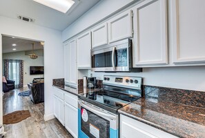 A modern kitchen with white cabinetry, a stainless steel oven, and a granite countertop.