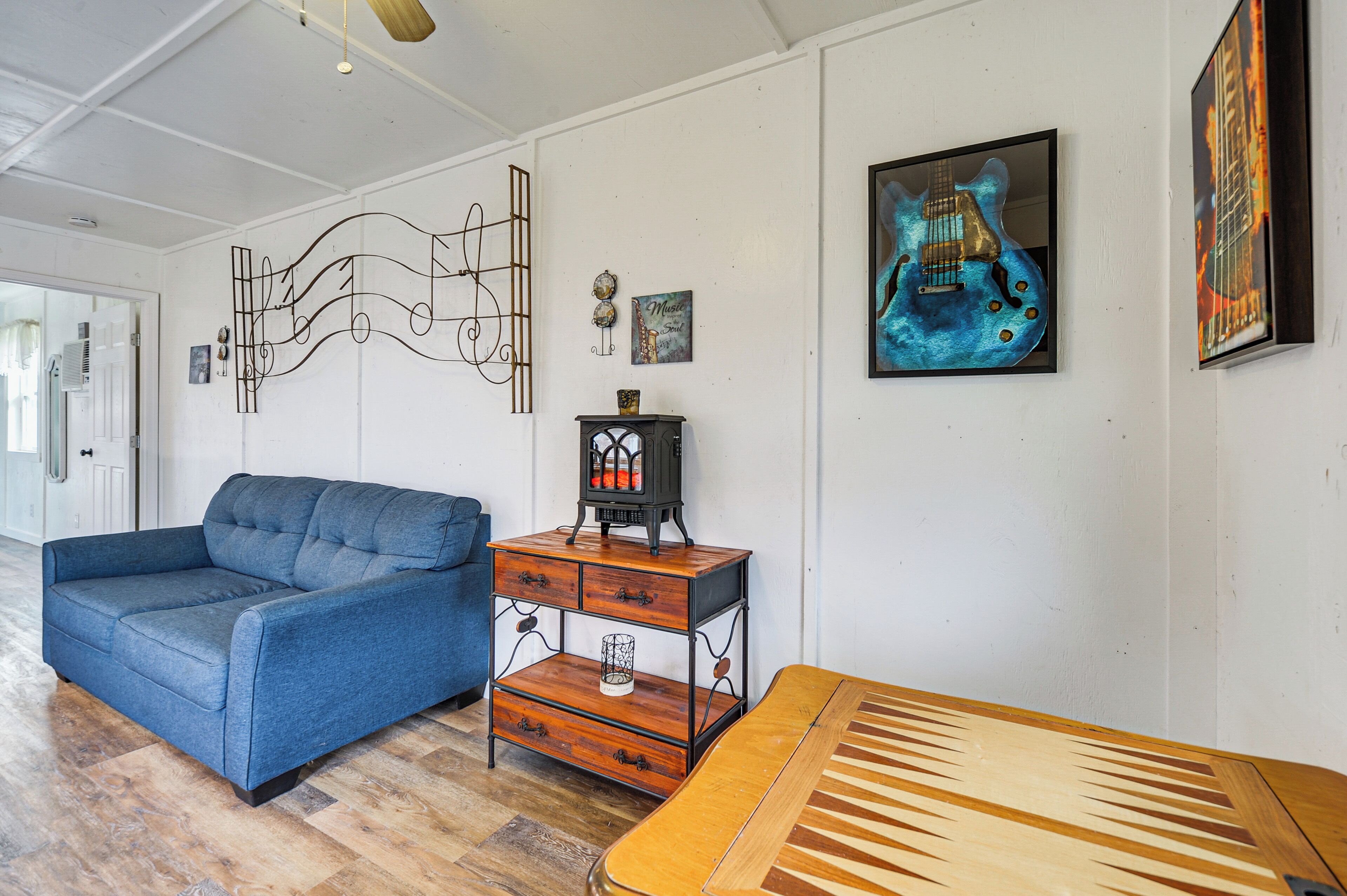 A room with a blue sofa, a wooden coffee table, and a wall-mounted guitar painting.