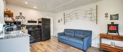 Eine Küche mit Kühlschrank, Backofen und Mikrowelle. Es gibt ein blaues Sofa und eine Holzkabine mit einem dekorativen Gegenstand darauf.