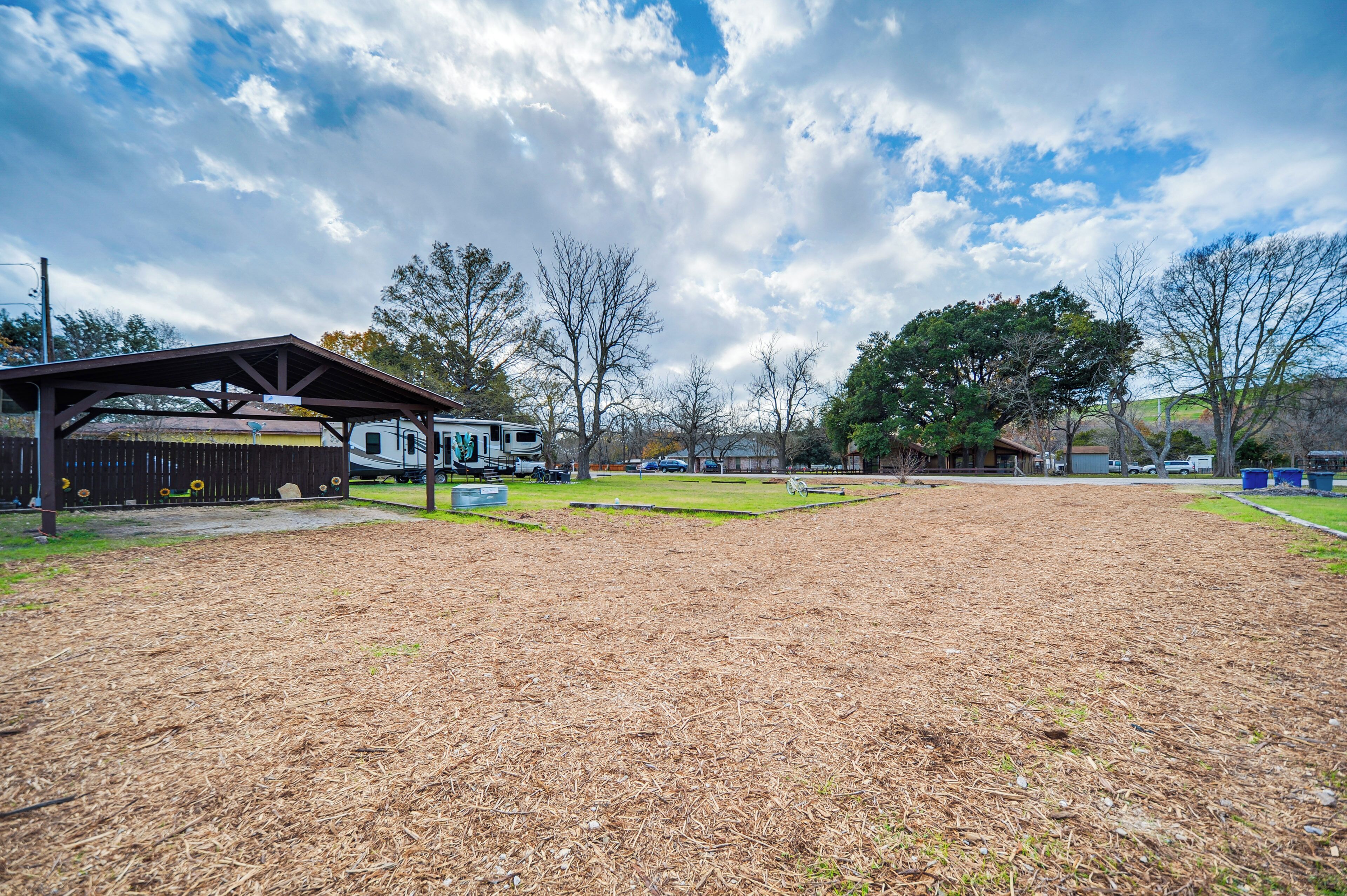 A campground with a covered picnic area, RV parking, and a grassy field.
