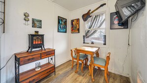 A room with a wooden dresser, a table with chairs, a guitar hanging on the wall, and framed pictures. - Cozy Canyon Lake Cottage Rental w/ Private Hot Tub (Canyon Lake)