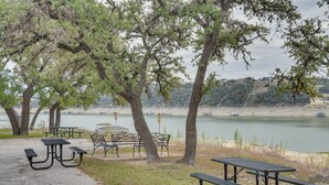 Un espace de pique-nique au bord du lac, équipé de tables et de bancs, entouré d’arbres et offrant une vue sur un lac paisible.