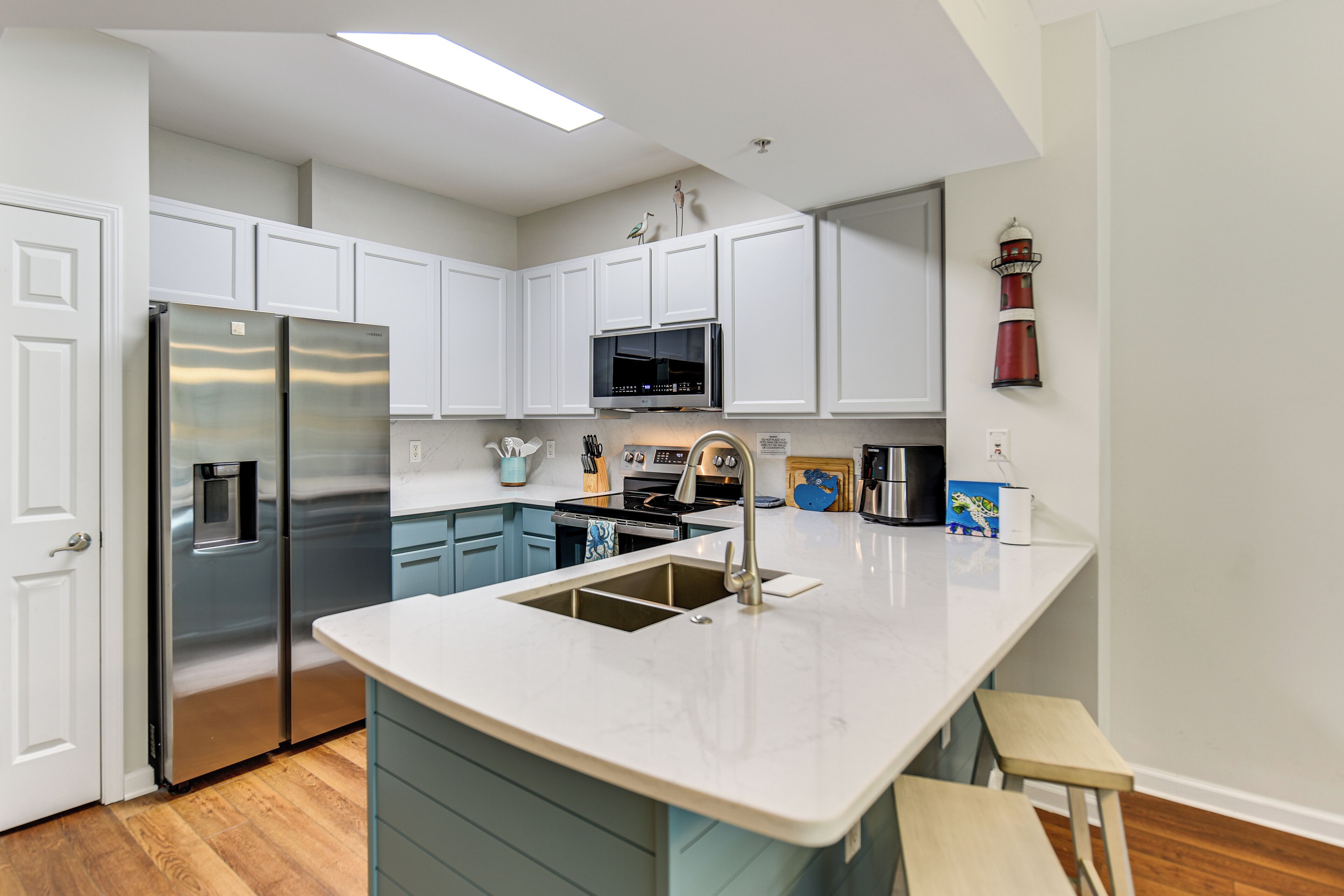 A modern kitchen with white cabinets, stainless steel appliances, and a central island with a sink.