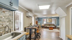 A kitchen with a stone backsplash, wooden flooring, and a dining area with stools. - Maine Vacation Rental < 1 Mi to Portage Lake Beach (Portage)