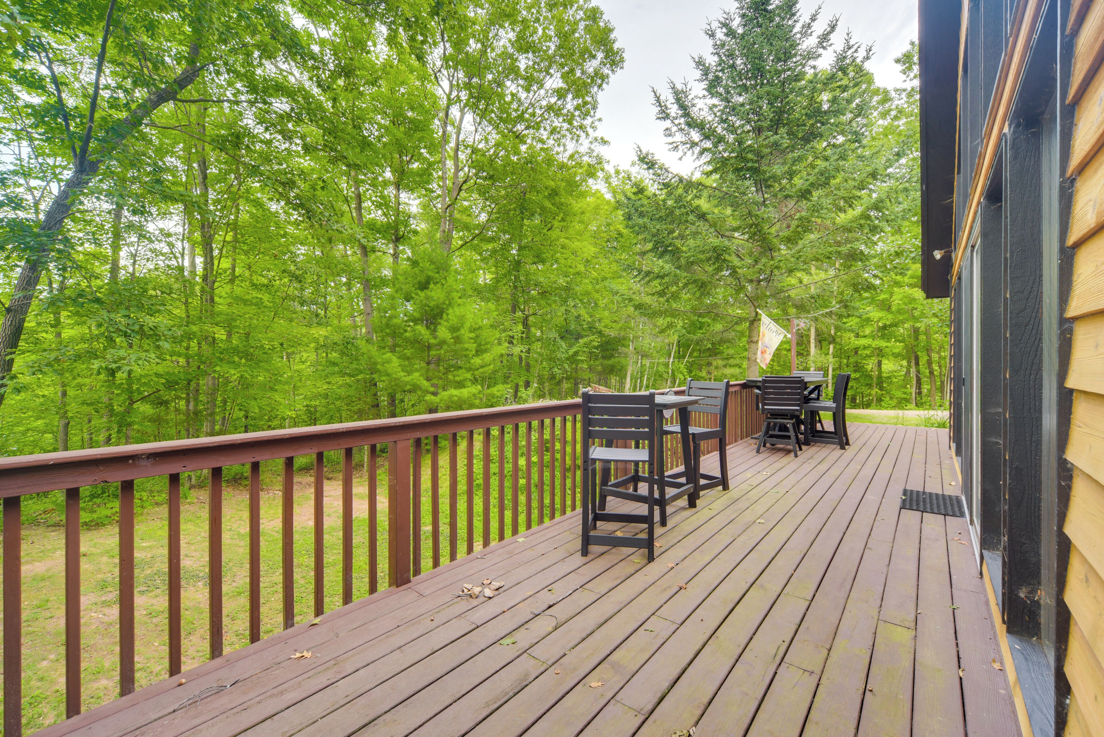 A wooden deck with outdoor furniture, surrounded by trees.