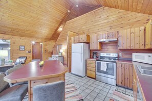 Une cabane en bois dotée d’une cuisine équipée d’un réfrigérateur, d’une cuisinière, d’un four à micro-ondes et de meubles de rangement en bois.