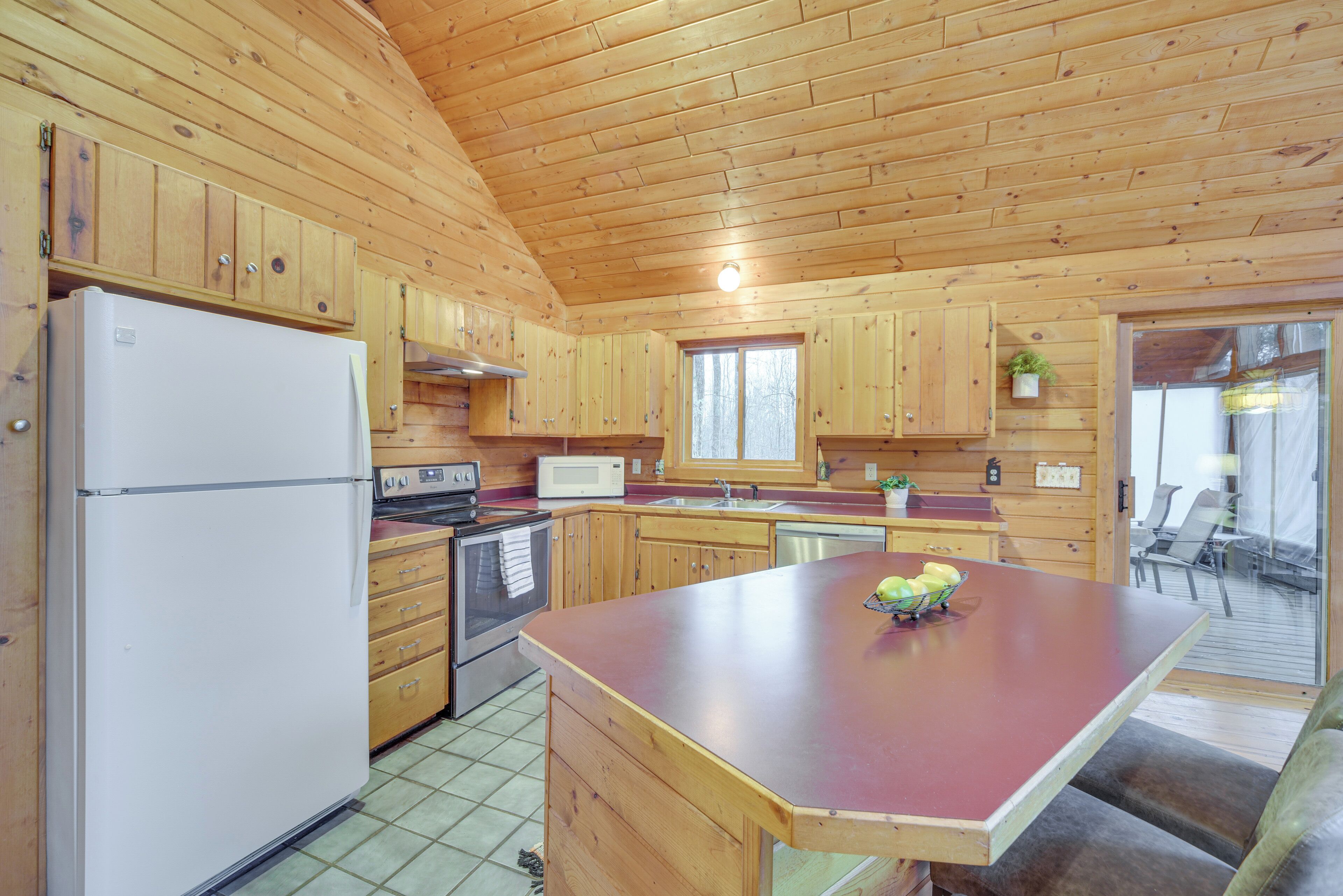 Una cocina estilo cabaña de madera con refrigerador, estufa, microondas y armarios de madera.