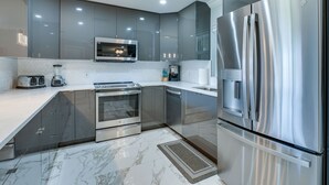 A modern kitchen with stainless steel appliances, a microwave, and a built-in oven. - Game Room + Screened Lanai: Pine Island Getaway! (Saint James City)