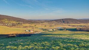 Un paysage rural caractérisé par des collines douces, un petit village et une rivière.