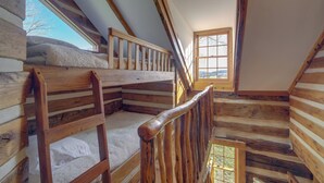 Un escalier en bois, doté d’une rampe, mène à une mezzanine où se trouve une fenêtre.