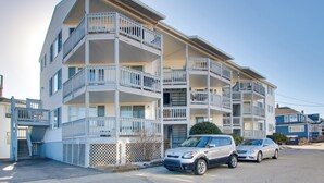Ein mehrgeschossiges Wohngebäude mit Balkonen, einer Garage und parkenden Autos.