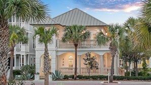 A two-story building with a balcony, palm trees, and a brick pathway.