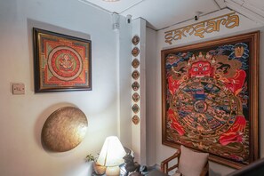A room with a large religious painting, a brass plate, and a lamp on a table. - Samsara Apartments by Babermahal Revisited (Kathmandu)
