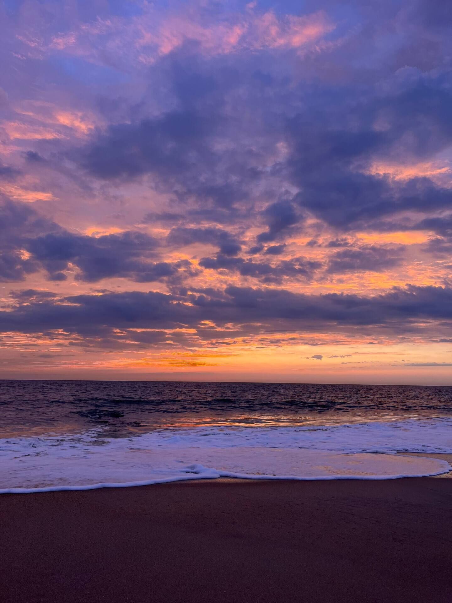 A beach with a sunset and ocean.