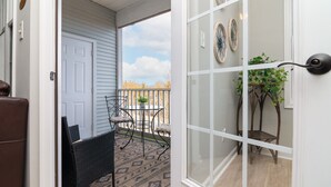 Un balcon avec une porte, une petite table et des chaises.