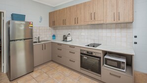 A modern kitchen with wooden cabinets, a stainless steel refrigerator, a built-in oven, and a microwave. - Forster Lodge 6: 1  BR, 1  BA Apartment in Forster, Sleeps 4 (Forster)