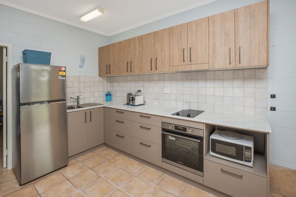 A modern kitchen with wooden cabinets, a stainless steel refrigerator, a built-in oven, and a microwave. - Forster Lodge 6: 1  BR, 0.5  BA Apartment in Forster, Sleeps 4 (Forster)