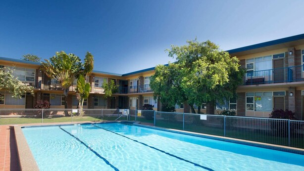 A swimming pool with a clear blue water surface, surrounded by a fenced area. - Forster Lodge 6: 1  BR, 1  BA Apartment in Forster, Sleeps 4 (Forster)