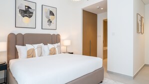 A modern bedroom with a large bed, two bedside tables, and abstract artwork on the walls. - HomesGetaway-Lavish2BR in CreekBayshore4 (Dubai)