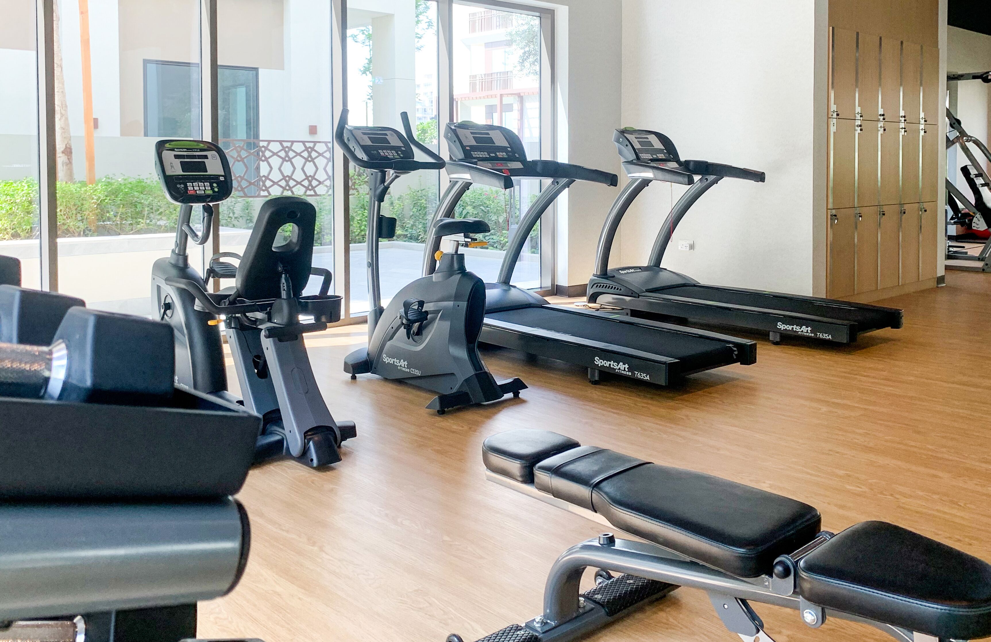 A gym with treadmills, an elliptical, and a bench.