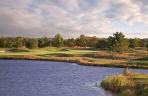 A golf course with a pond, trees, and a cloudy sky. - New Listing * Bear Trap Dunes Resort: Beautiful Vacation House (Ocean View)