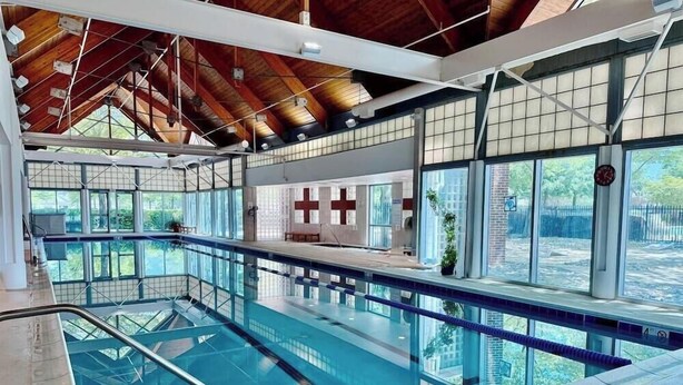 An indoor swimming pool with a wooden ceiling, large windows, and a lifeguard station. - New Listing * Bear Trap Dunes Resort: Beautiful Vacation House (Ocean View)