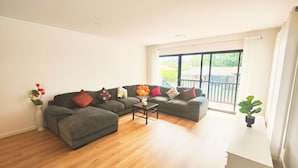 Ein modernes Wohnzimmer mit einem Ecksofa, einem Couchtisch und einer Topfpflanze.